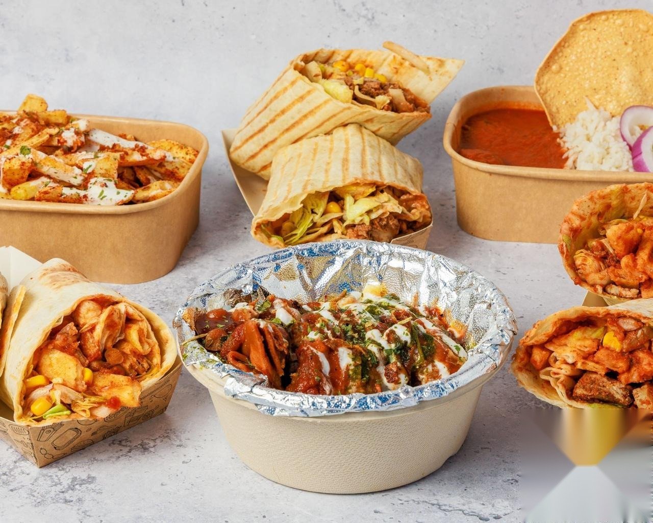 A spread of Miss India Oslo dishes including wraps, fries and curry ready for catering