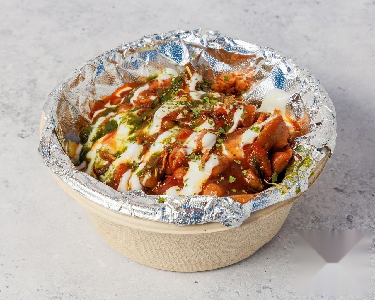 Samosa Chaat topped with yoghurt, mint chutney, tamarind chutney and coriander
